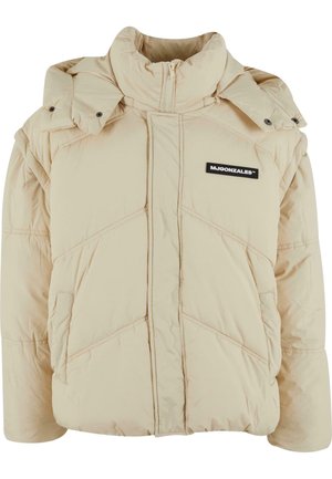 Beige pufferjakke med høj krave, skrå syninger, lynlås foran og patch-logo. Har aftagelig hætte og sidelommer.