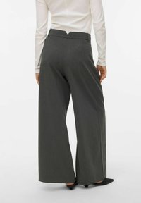 Szare spodnie o szerokich nogawkach z dopasowanym krojem, z wysokim stanem i subtelną fakturą. Ozdobione detalem w kształcie litery V z tyłu.