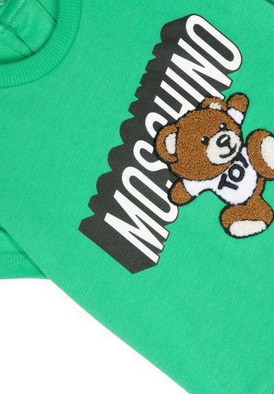 T-shirt in cotone verde con un patch a forma di orsetto marrone e il bold "Moschino" in nero, con un design giocoso e un classico collo rotondo.