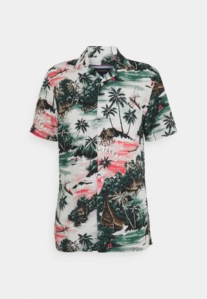Chemise à manches courtes boutonnée avec un imprimé tropical comprenant des palmiers, des huttes, des bateaux, et des couleurs rose et vert.