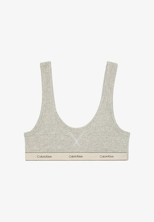 Seno grigio chiaro con spalline larghe, scollatura rotonda e tessuto morbido. Presenta una fascia beige a contrasto con il testo "Calvin Klein".