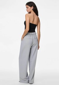 Svart strapless topp i kombination med ljusgrå, hög midja, vida byxor med elastiskt midjeband och två bakfickor. Slät textur.