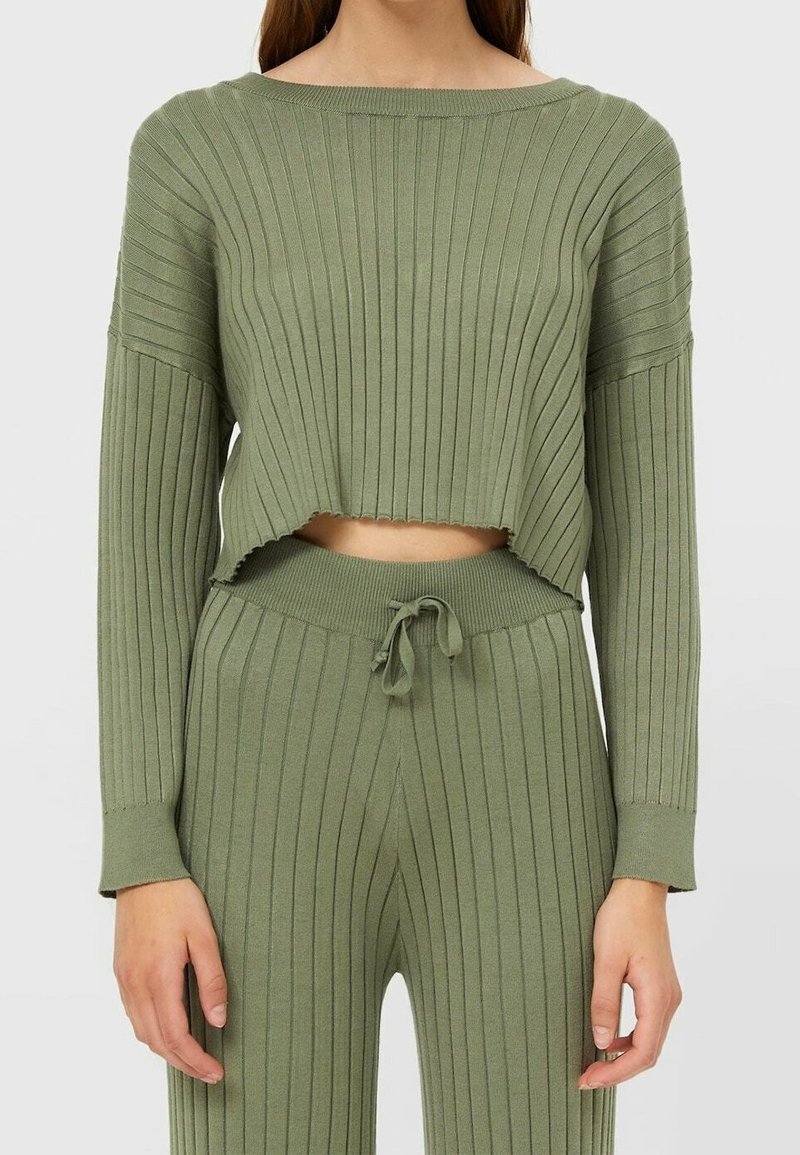 Pull court en maille côtelée vert olive avec de longues manches et un col arrondi, associé à un pantalon à cordon assorti. Texture douce, rayures verticales.
