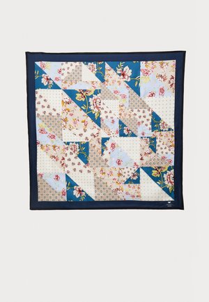 Siuvinėta sieninė dekoracija su gėlių ir geometriniais raštais mėlynos, kreminės ir smėlio spalvos tonais, apgadinta tamsiai mėlynu rėmeliu.