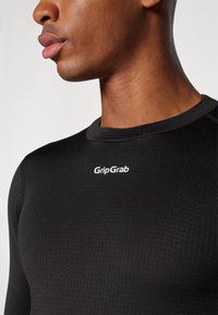 Schwarzes Langarmshirt aus elastischem Material. Mit Rundhalsausschnitt und strukturiertem Muster. "GripGrab"-Logo in Weiß auf der Brust.