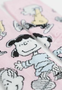 Calzini rosa con personaggi dei cartoni animati in bianco e nero, con dettagliati motivi e trame che raffigurano scene fantasiose.