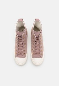 Zapatillas de caña alta en suave tela rosa con ojales dorados, punteras de caucho blanco y acentos texturizados. Diseño redondeado con cordones.