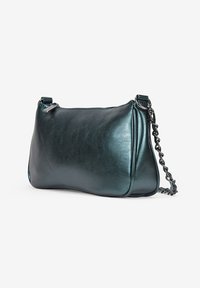 Bolso de mano de cuero en color verde azulado con una textura suave, forma redondeada y una correa de cadena plateada. Presenta un cierre de cremallera y costuras mínimas.