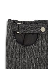 Black denim pants feature a round pocket, silver hardware, and a textured finish with a label reading "Karl Lagerfeld Jeans."
