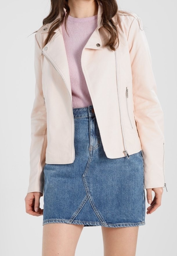 Helle rosa Kunstleder-Motorradjacke mit asymmetrischem Reißverschluss, zwei seitlichen Taschen, getragen über einem lavendelfarbenen Oberteil und einem Jeansrock.