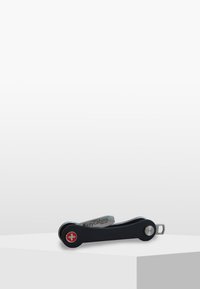 Couteau suisse avec un corps en métal noir, des accents argentés, un emblème rouge et un design élégant et courbé pour la fonctionnalité et la portabilité.