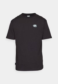 T-shirt noir à manches courtes de Puma avec col rond et petit logo de la marque sur le côté gauche de la poitrine, sur fond blanc.
