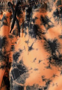 Narančasto-crne kupaćice s efektom tye-dye s elastičnim pojasom i crnom vezicom. Imaju kontrastne narančaste šavove i glatku teksturu.