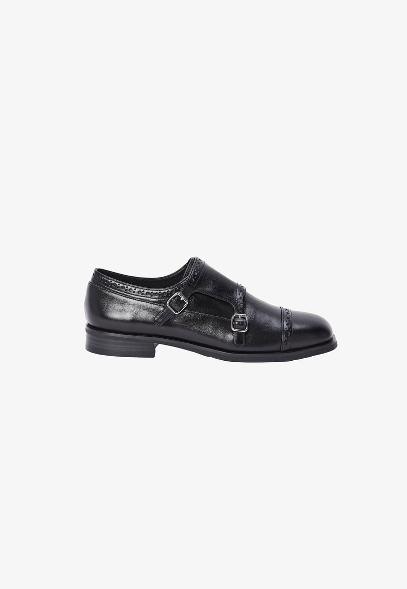 Chaussure en cuir noir avec deux accents de boucle, une couture décorative en haut et un bout arrondi. La semelle est plate et légèrement texturée.
