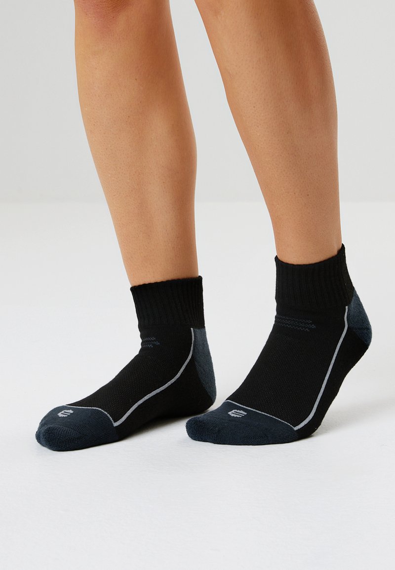 Svarta ankelsockor med ribbat manschett, grå accenter och ljusa sömnadsdetaljer. Tillverkade av ett flexibelt, andningsbart material.