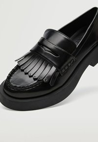 Sorte læder loafers med frynse detalje, vævet kant og en tyk gummisål. Har en afrundet tå og glat overflade.