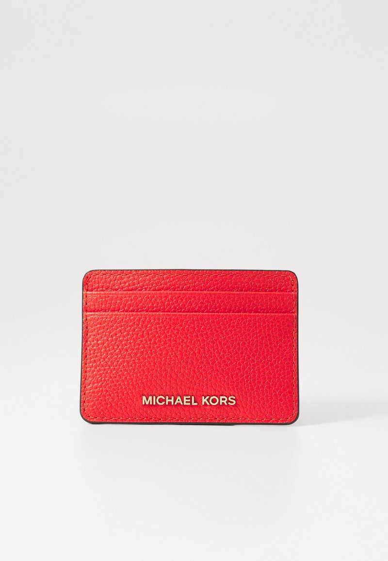 Raudonas odinis kortelių laikiklis su tekstūruota paviršiumi, keturiomis kortelių vietomis ir iškilusiu "MICHAEL KORS" logotipu auksinės spalvos apačioje.