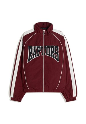 Vinröd jacka med dragkedja, vita ränder på axlar och ärmar, elastiska muddar och fåll samt "RAPTORS"-text i svart och vitt över bröstet.