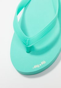 Teal flip-flop made of rubber with textured straps and a smooth footbed. Brand name printed in white on the sole. Designed for casual wear.