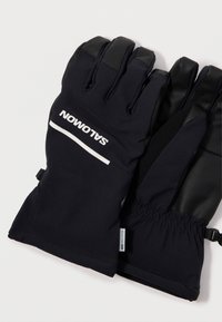 Luvas pretas com um tecido suave e texturizado, e acentos de couro liso. Apresenta um logotipo, punho elástico e uma faixa ajustável para um encaixe seguro.