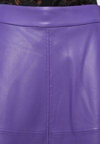 Violetas ādas svārki ar gludu faktūru, piedāvājot pieguļošu dizainu, redzamas šuves un augstu jostasvietu.