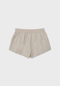 Shorts décontractés beige clair avec une ceinture élastique, une longueur courte et une coupe ample sur un fond uni.