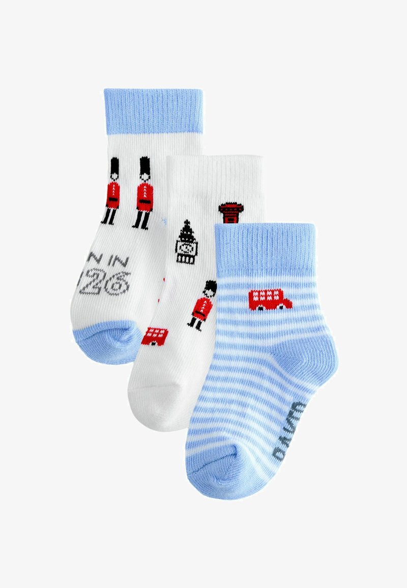 Trois paires de chaussettes : une blanche avec des motifs de gardes en rouge et noir, une autre blanche avec des bus rouges et des monuments, et une paire bleu rayé avec des bordures bleues.