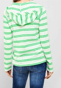 Zielona i biała w paski, długa koszula z kapturem i kangurzą kieszenią, w połączeniu z niebieskimi dżinsami. Luźny i lekki fason.