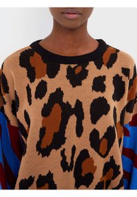 Maglione lavorato a maglia con stampa leopardata nei toni del beige, marrone e nero, dotato di un collo a coste nero e accenti colorati blu e rosso sulle maniche.