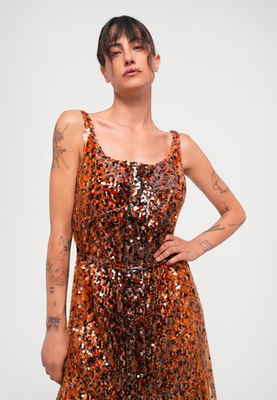 Rochie cu paiete, cu decolteu pătrat, având un model de leopard portocaliu și negru, detalii cu nasturi și talie ajustată. Modelul pozează cu încredere.