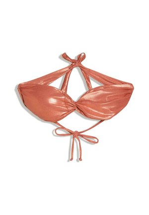 Junge Frau mit nassen Haaren, die ein glänzendes, rostfarbenes Bandeau-Bikinitop trägt, steht vor dem sonnenbeschienenen Meer und entfernten Inseln bei Sonnenuntergang.