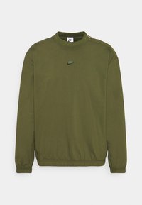 Olivově zelený pulover Nike s dlouhými rukávy, elastickými manžetami a lemem, a malým logem Nike umístěným na hrudi.