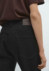 Zwarte denim jeans met een rechte pasvorm. Kenmerken zijn onder andere achterzakken, een gestructureerde leren merkpatch en subtiele stikdetails.