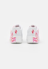 Białe sneakersy z różowymi abstrakcyjnymi wzorami po bokach, z teksturowaną powierzchnią i wyściełanym kołnierzem dla wygody.