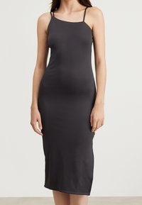 Černé, těsně přiléhající midi šaty s tenkými ramínky, vyrobené z hladkého materiálu, s jednoduchým a čistým designem. Bez vzorů nebo akcentů.