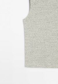 Nahaufnahme eines hellgrauen, gestrickten ärmellosen Oberteils mit gerippter Textur und kleinen schwarzen Sprenkeln vor schlichtem weißem Hintergrund.