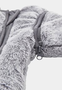 Gray zip-up jacket with soft, fuzzy texture. Features a black zipper and ribbed hem. Material is plush, providing warmth and comfort.