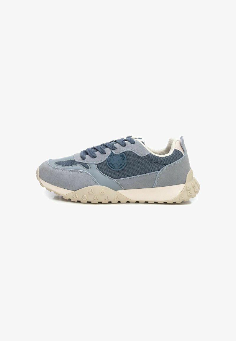 Zapatilla en materiales gris claro y marino, presenta una suela de goma texturizada con un patrón triangular, puntera redondeada y cordones planos.