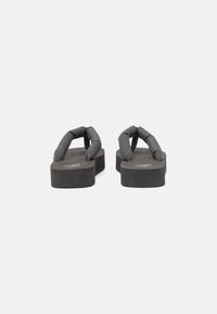 Svarta flip-flops med en tjock, texturerad sula och vadderade remmar, som har en slät yta och minimalistisk design.