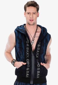 Kapuzenloser ärmelloser Reißverschluss-Weste aus schwarzem und blauem Mesh-Material mit grafischem Design, Fronttaschen und metallischen Logo-Details.