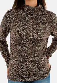 Top de manga larga con estampado de leopardo y cuello drapeado, hecho de una tela suave, que presenta un patrón animal en tonos cálidos de marrones y negros.