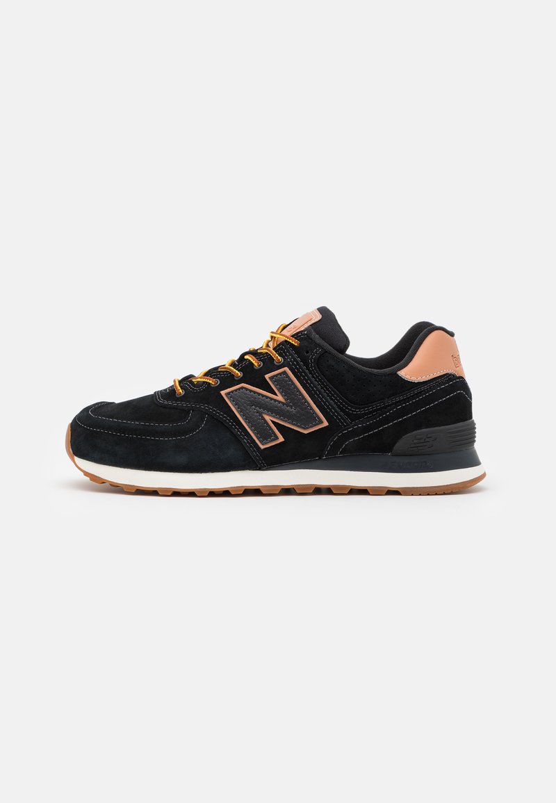 Baskets en suède noir avec des accents oranges, dotées d'une semelle rembourrée, d'un logo "N" bien en vue et de détails texturés sur le dessus.