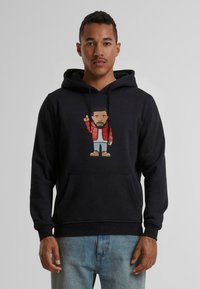 Zwarte hoodie met een voorste kangoeroezak en een illustratie van een personage in een rode pufferjack; gemaakt van een katoenmix met een gestructureerde afwerking.