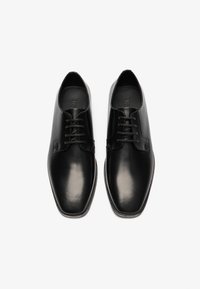 Zapatos de vestir de cuero negro con un acabado suave, punta redondeada y diseño de cordones. Presentan costuras sutiles y una suela de perfil bajo.