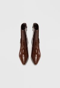 Bottines marron, brillantes, avec un motif en cuir de crocodile, à bout pointu et fermeture éclair sur le côté. Texture lisse et design épuré.