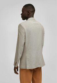 Heller beiger Blazer aus strukturiertem Stoff, mit ausgeformten Schultern und doppelter Schlitze hinten. Verfügt über goldfarbene Knopf-Details an den Manschetten.