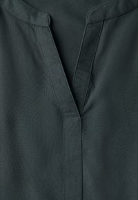 Blusa verde scuro con scollatura a V, pattina di bottoni e texture del tessuto liscia. Presenta cuciture eleganti lungo il colletto e l'orlo.