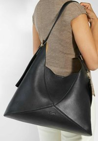 Large black leather handbag with a triangular shape, featuring minimal stitching, a single shoulder strap, and a smooth texture.