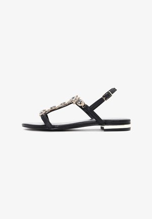 Black flat sandals with a T-strap design, featuring beaded embellishments and a small block heel with a silver accent. Smooth leather finish.