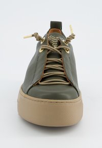 Baskets en cuir vert avec accents dorés, tige texturée, semelle en caoutchouc beige et laçage à l'avant. Remarquables pour leur design de languette unique.
